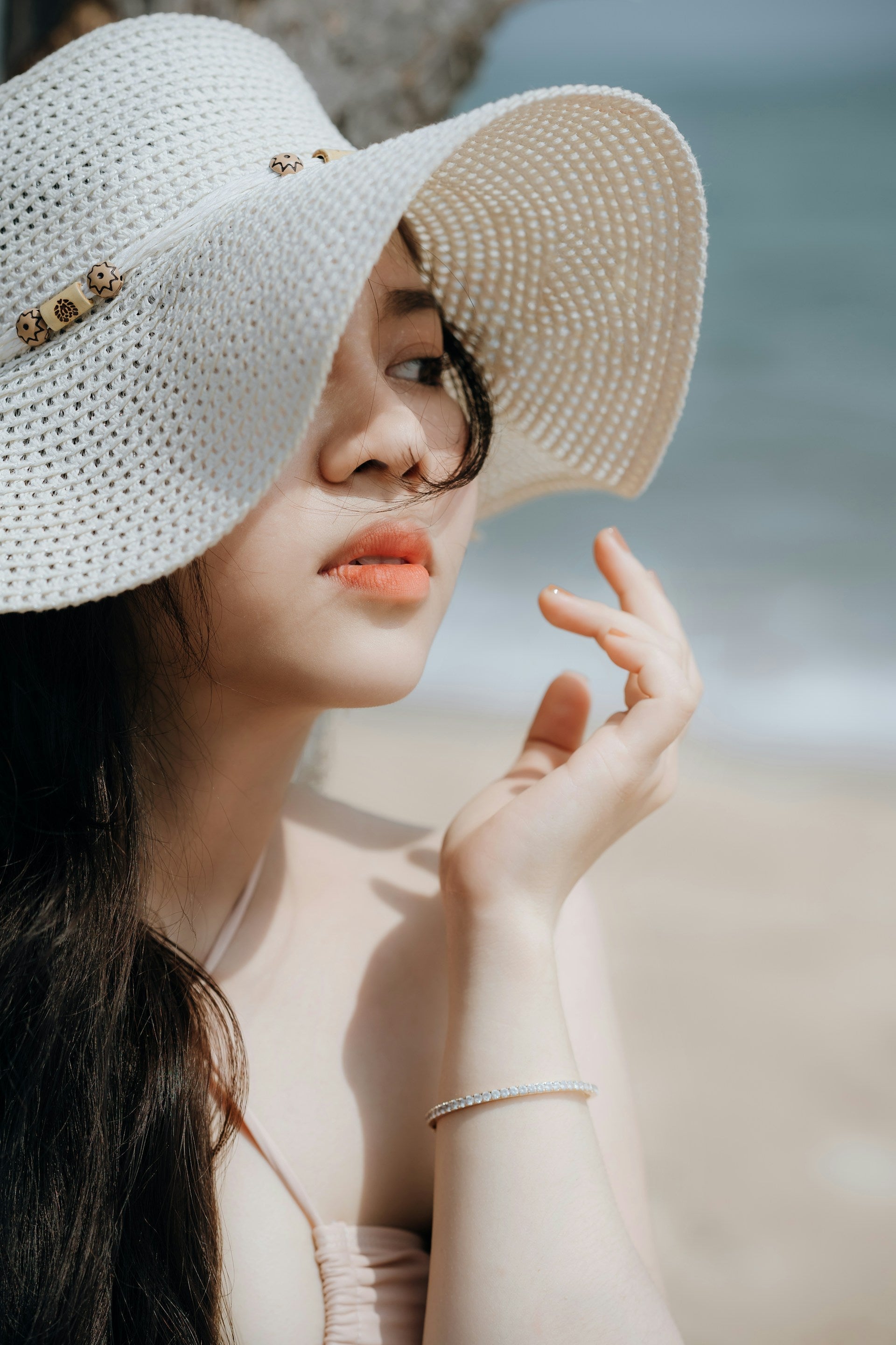 Femme avec un chapeau élégant blanc sur la plage.