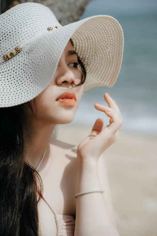 Femme avec un chapeau élégant blanc sur la plage.