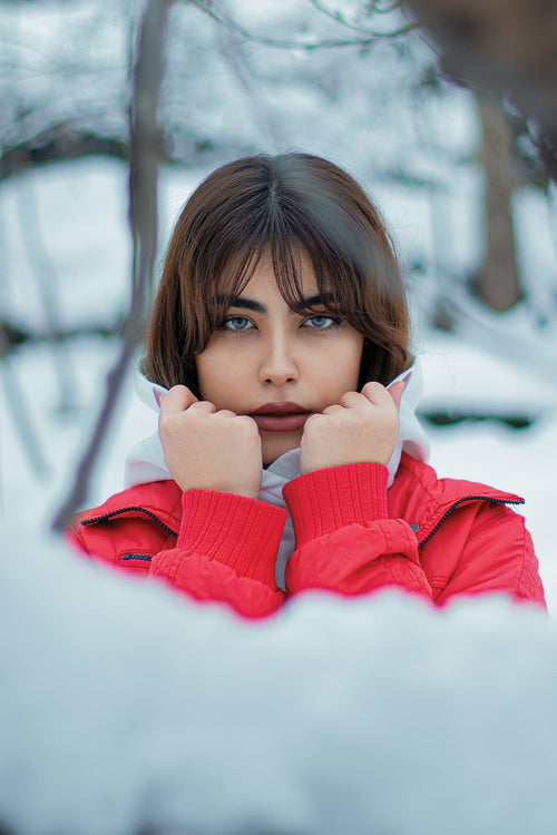  Femme en veste rouge debout dans un paysage enneigé.